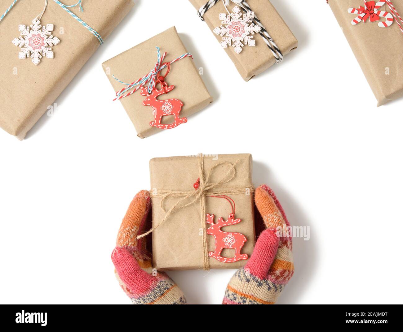 las manos femeninas en manoplas tejidas sostienen una caja envuelta en papel marrón y atada con una cuerda sobre un fondo blanco, superior stock - Alamy