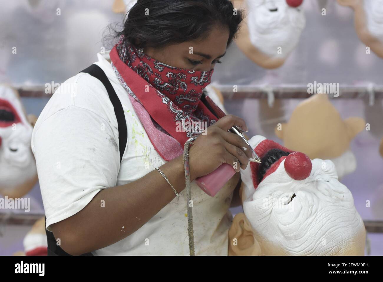 Una trabajadora es vista pintando una máscara de látex de un payaso