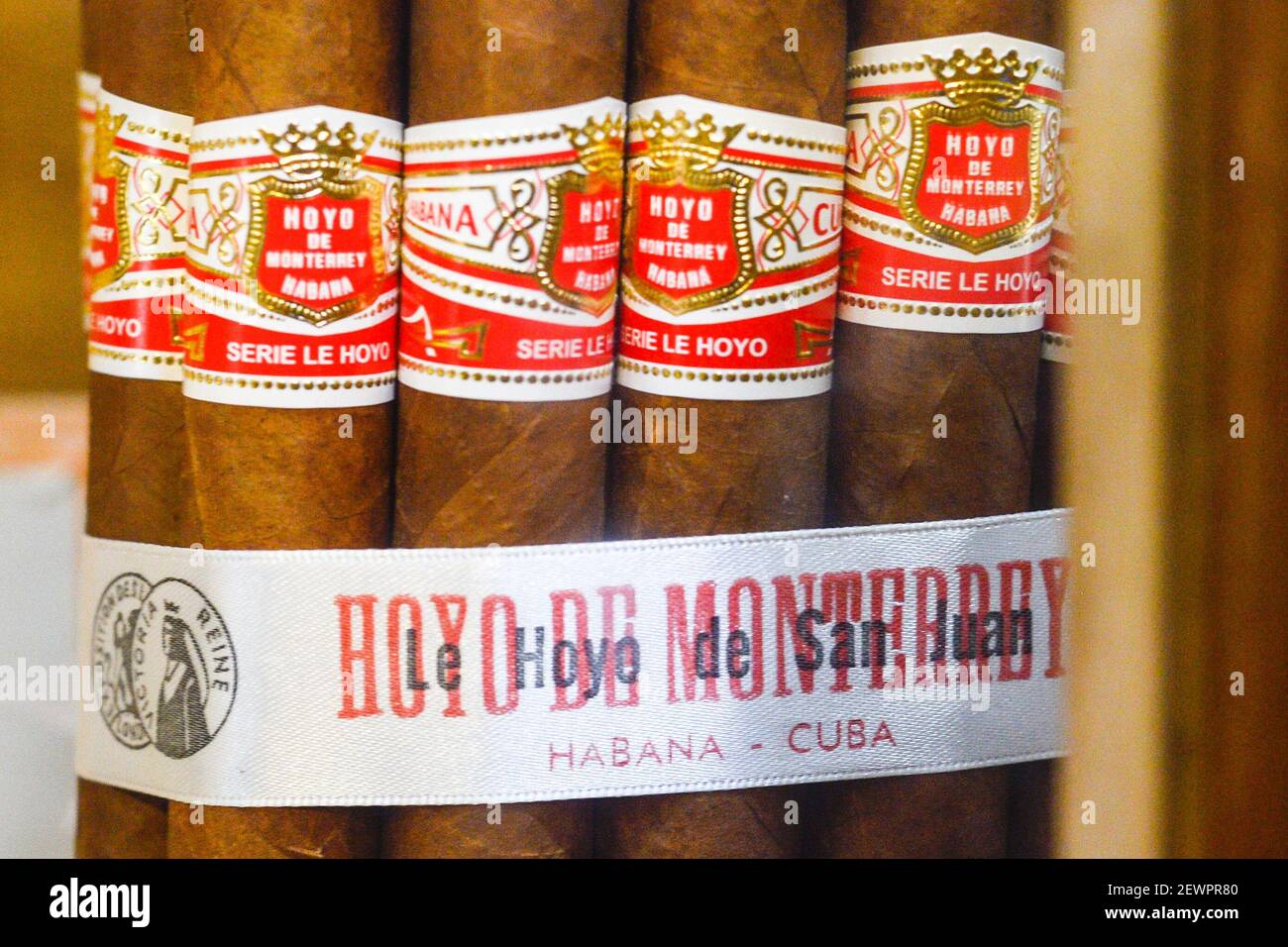 Cigarros cubanos en exhibición en una ventana de tienda. Esos cigarros son rodados de hojas de tabaco que se encuentran en todo el país de Cuba. El relleno, el aglutinante y la envoltura pueden provenir de diferentes porciones de la isla. Toda la producción de cigarros en Cuba es controlada por el gobierno cubano, y cada Marca puede ser rodada en varias fábricas diferentes en Cuba. Cuba produce cigarros hechos a mano y a máquina. Todas las cajas y etiquetas están marcadas como Hecho en Cuba. Los cigarros hechos a máquina terminados a mano añaden a Hecho un mano, mientras que los puros completamente hechos a mano dicen totalmente un mano en el texto del guión, sin embargo Foto de stock