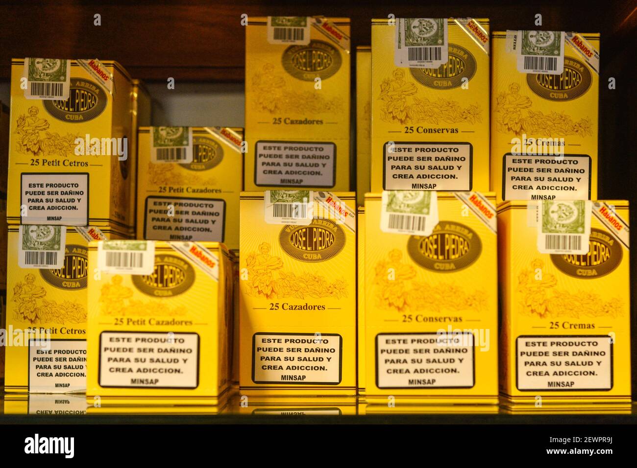 Cigarros cubanos en exhibición en una ventana de tienda. Esos cigarros son rodados de hojas de tabaco que se encuentran en todo el país de Cuba. El relleno, el aglutinante y la envoltura pueden provenir de diferentes porciones de la isla. Toda la producción de cigarros en Cuba es controlada por el gobierno cubano, y cada Marca puede ser rodada en varias fábricas diferentes en Cuba. Cuba produce cigarros hechos a mano y a máquina. Todas las cajas y etiquetas están marcadas como Hecho en Cuba. Los cigarros hechos a máquina terminados a mano añaden a Hecho un mano, mientras que los puros completamente hechos a mano dicen totalmente un mano en el texto del guión, sin embargo Foto de stock