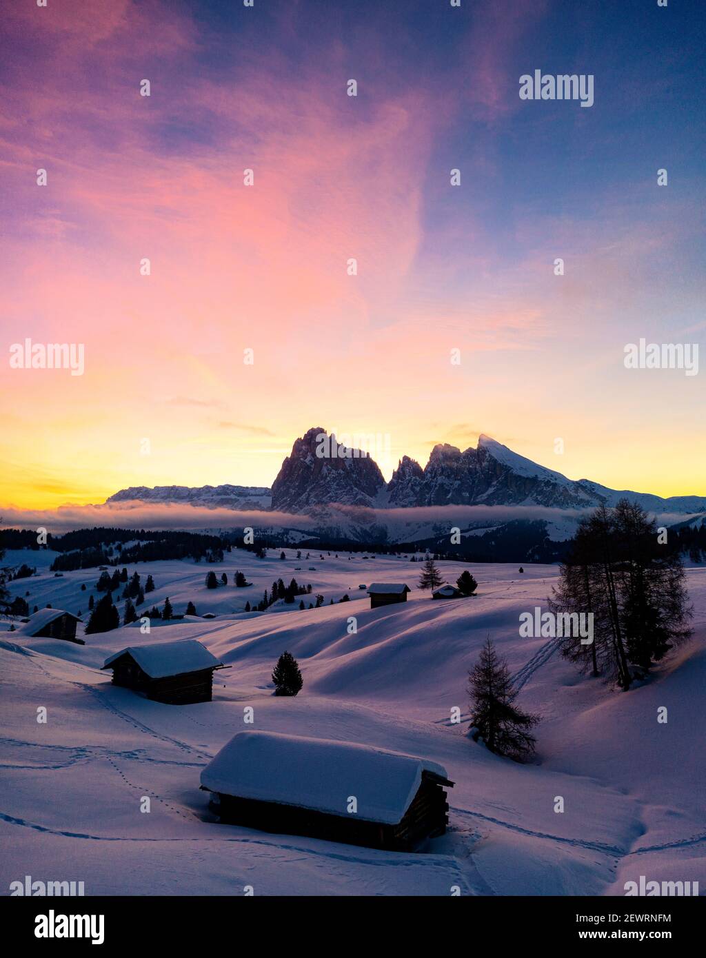 Cabañas de montaña cubiertas de nieve al amanecer con Sassopiatto y Sassolungo en el fondo, Seiser Alm, Dolomitas, Tirol del Sur, Italia, Europa Foto de stock