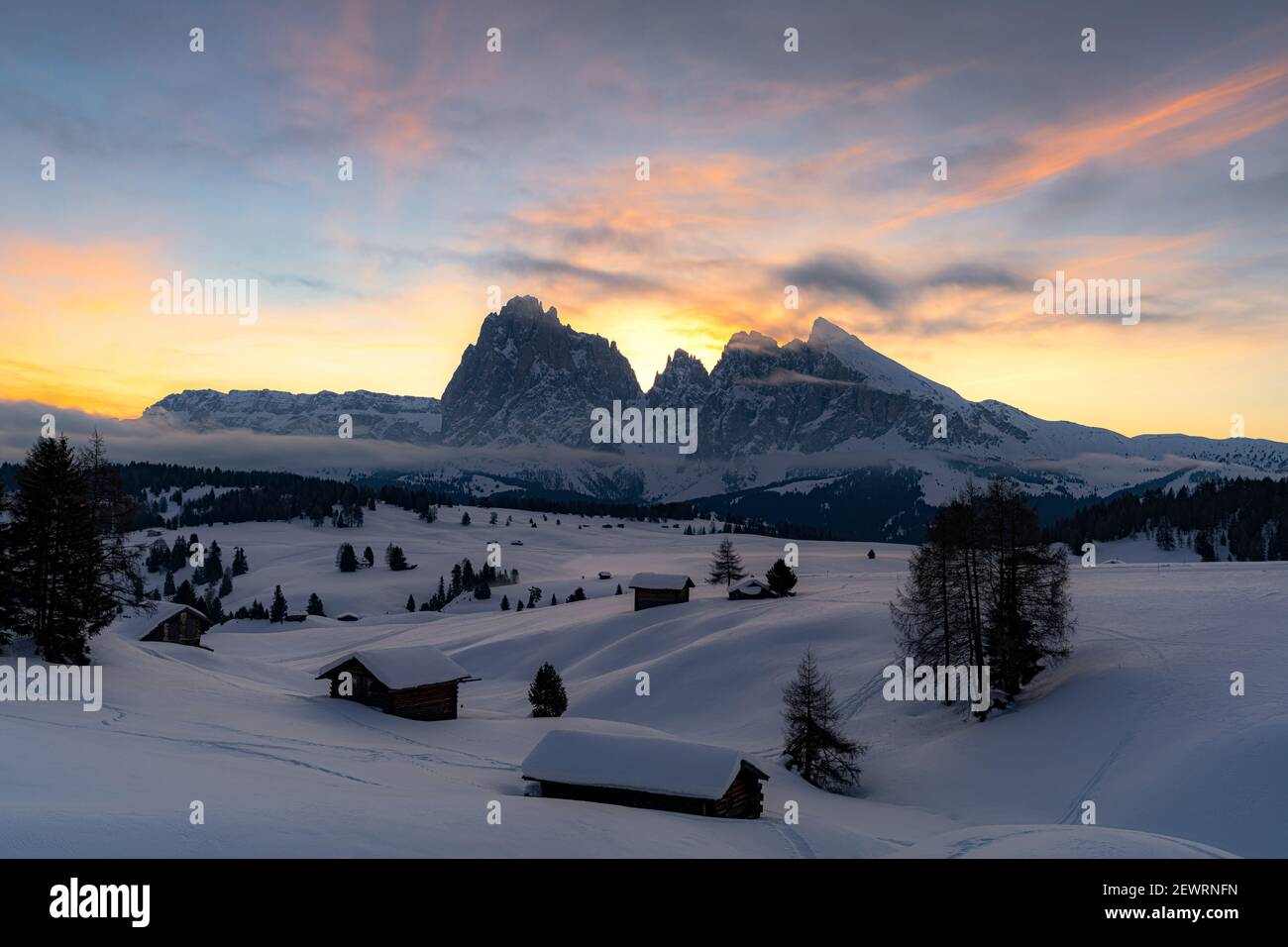 Cabañas de montaña cubiertas de nieve con Sassopiatto y Sassolungo en el fondo al amanecer, Seiser Alm, Dolomitas, Tirol del Sur, Italia, Europa Foto de stock