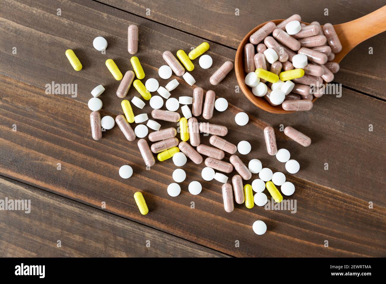 Vista superior de un surtido de píldoras, tabletas y cápsulas de medicina farmacéutica sobre un fondo de madera oscura. Foto de stock