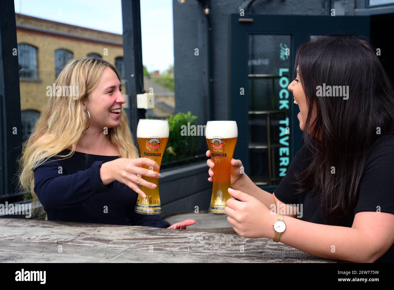 Dos mujeres bebiendo cerveza y riendo en un pub en Camden, Londres Foto de stock
