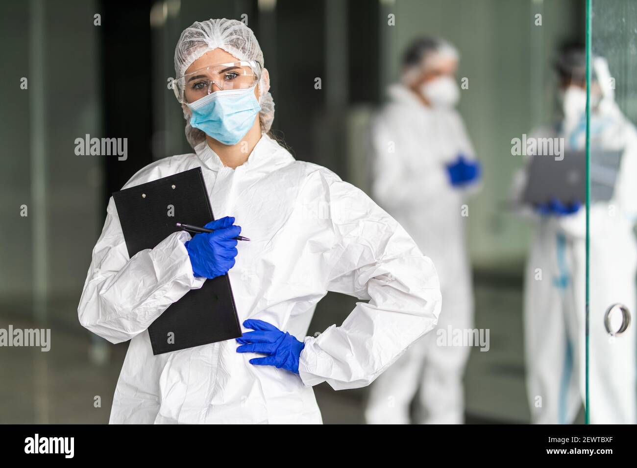 Empleados de control de enfermedades en ropa protectora durante la epidemia de coronavirus Coivd-19 en una clínica Foto de stock