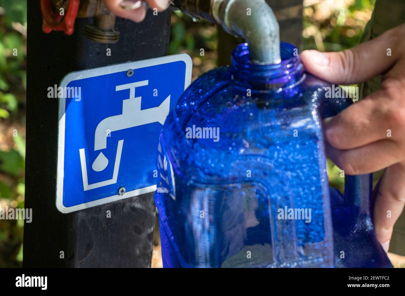 22 de agosto de 2021 - Bolton, QC, Canadá: Llenado de agua potable en botella reutilizable en un punto de agua potable en un campamento, el hombre manos holeando un contenedor Foto de stock