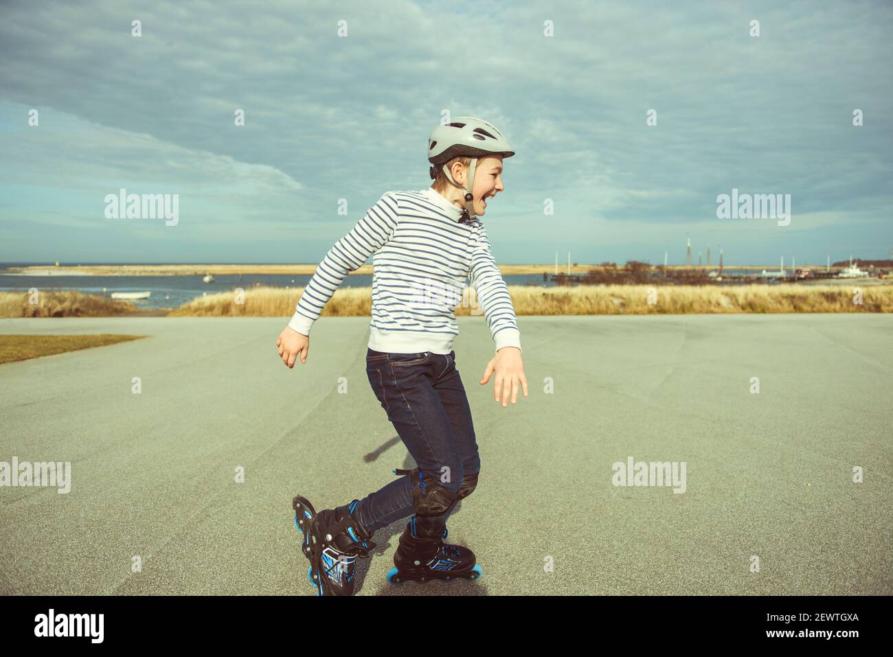 Feliz adolescente niño en casco, patines en línea y equipo de seguridad feliz aprendizaje patinaje día soleado en verano Fotografía de - Alamy