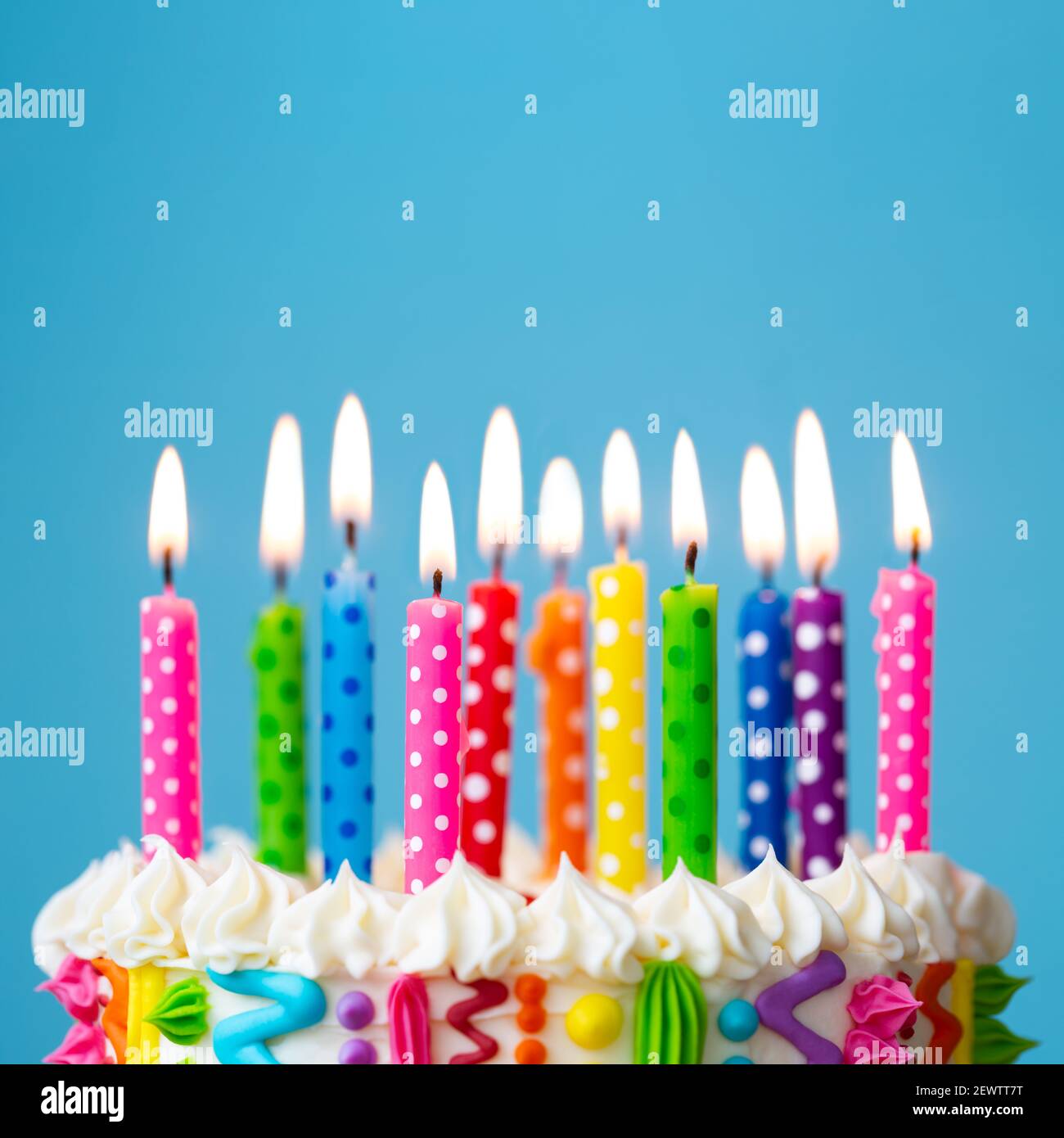 Pastel de cumpleaños colorido con velas de color arco iris Foto de stock