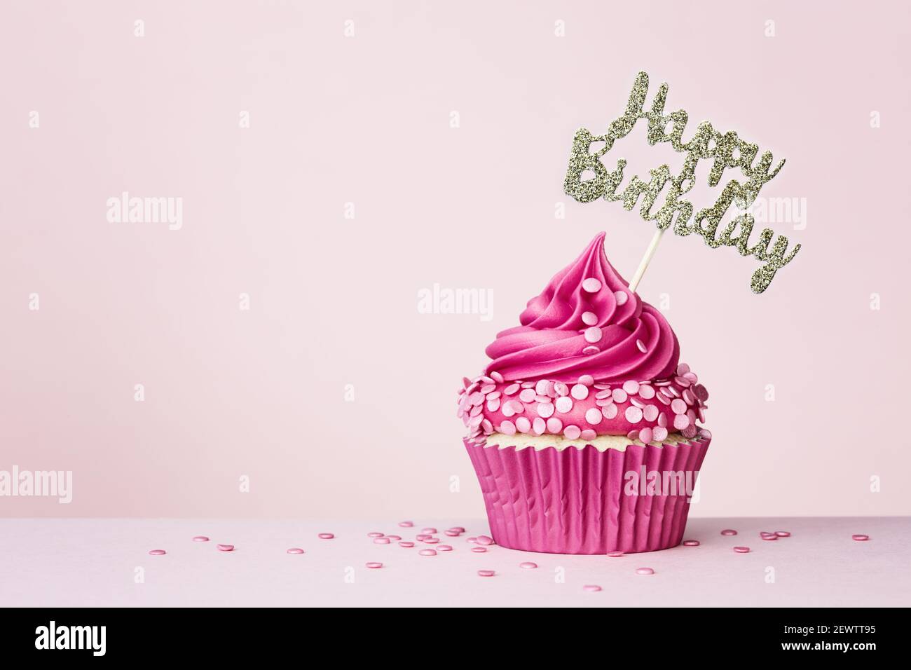 Fondo de cumpleaños con cupcake de celebración con banner de cumpleaños feliz encendido un fondo rosa Foto de stock