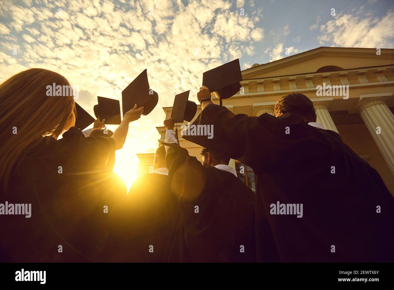 Grupo de graduados felices de pie y con diplomas en criado sin duda sobre la puesta de sol Foto de stock