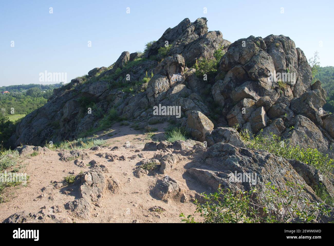 Piedras afiladas. Rocas afiladas en la cima de una colina en la región de Nikolaev en Ucrania en un brillante día de verano. Cielo azul sin nubes sobre un pico de montaña. Foto de stock