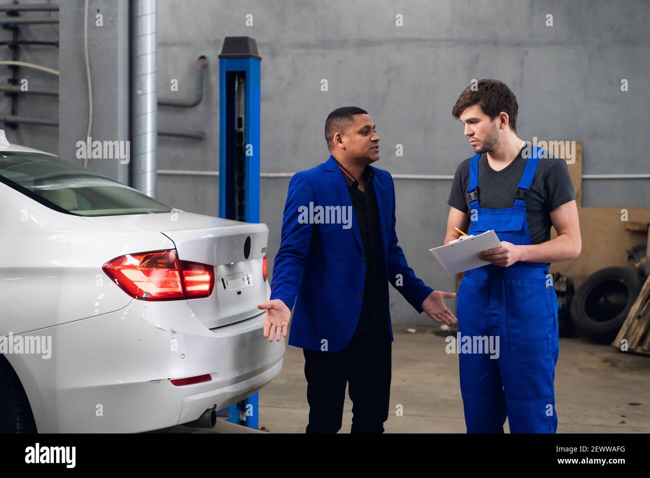 Mecánico hablando con un cliente sobre una reparación de un coche Foto de stock