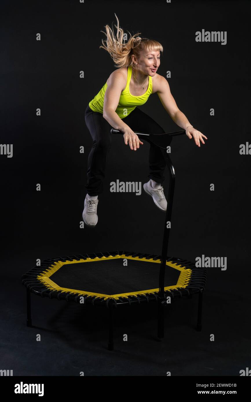 Chica en un trampolín de fitness sobre un fondo negro en una camiseta  amarilla deporte trampolín, equipo de actividad femenina estilo de vida  vitalidad, lindo rebotador Fotografía de stock - Alamy