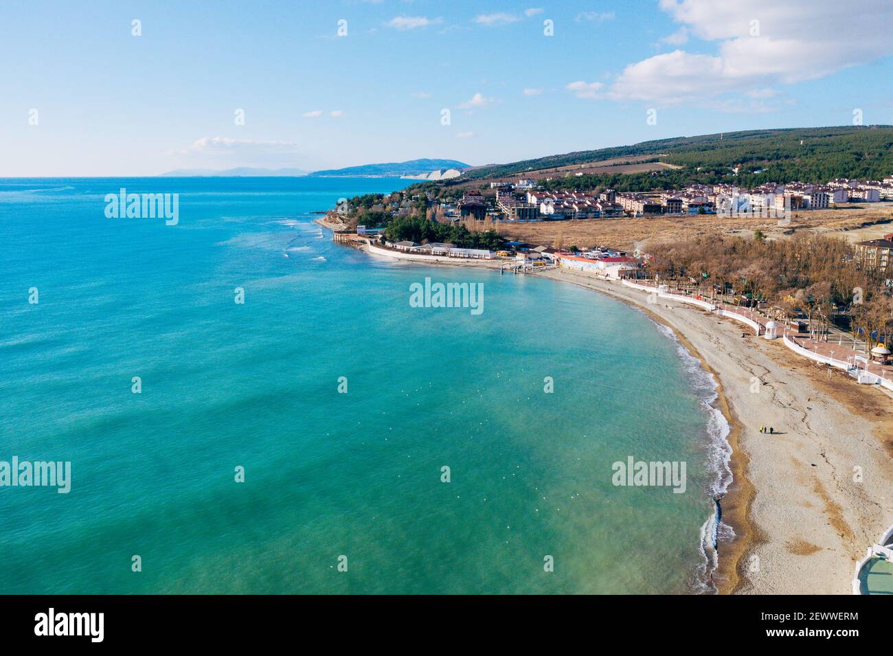 Vista aérea de la costa del mar con playa de arena y pequeños edificios. Hermoso paisaje azul y azul marino de drone. Foto de stock