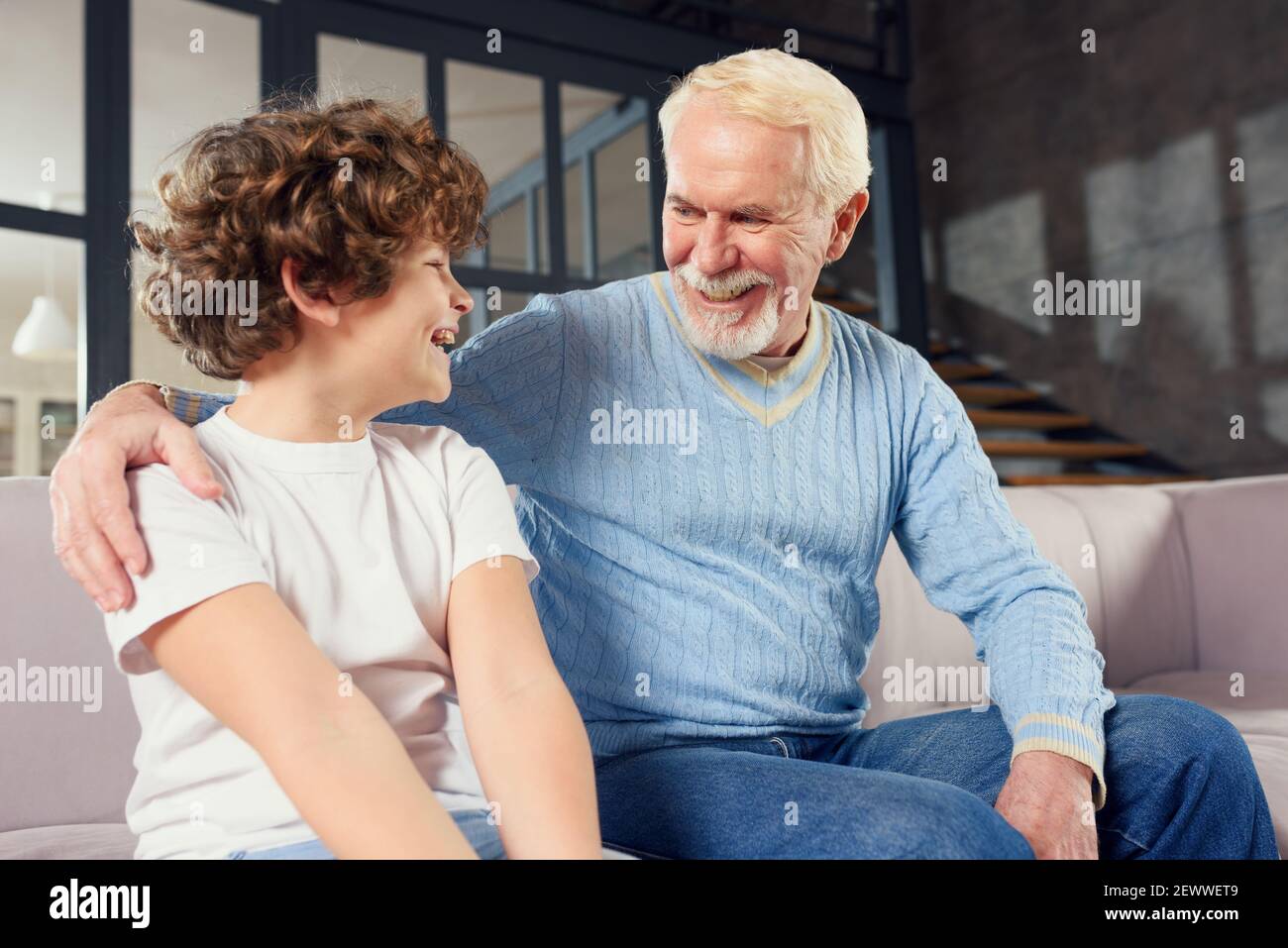 Abuelo e nieto que disfruta juntos en el sofá en casa Foto de stock
