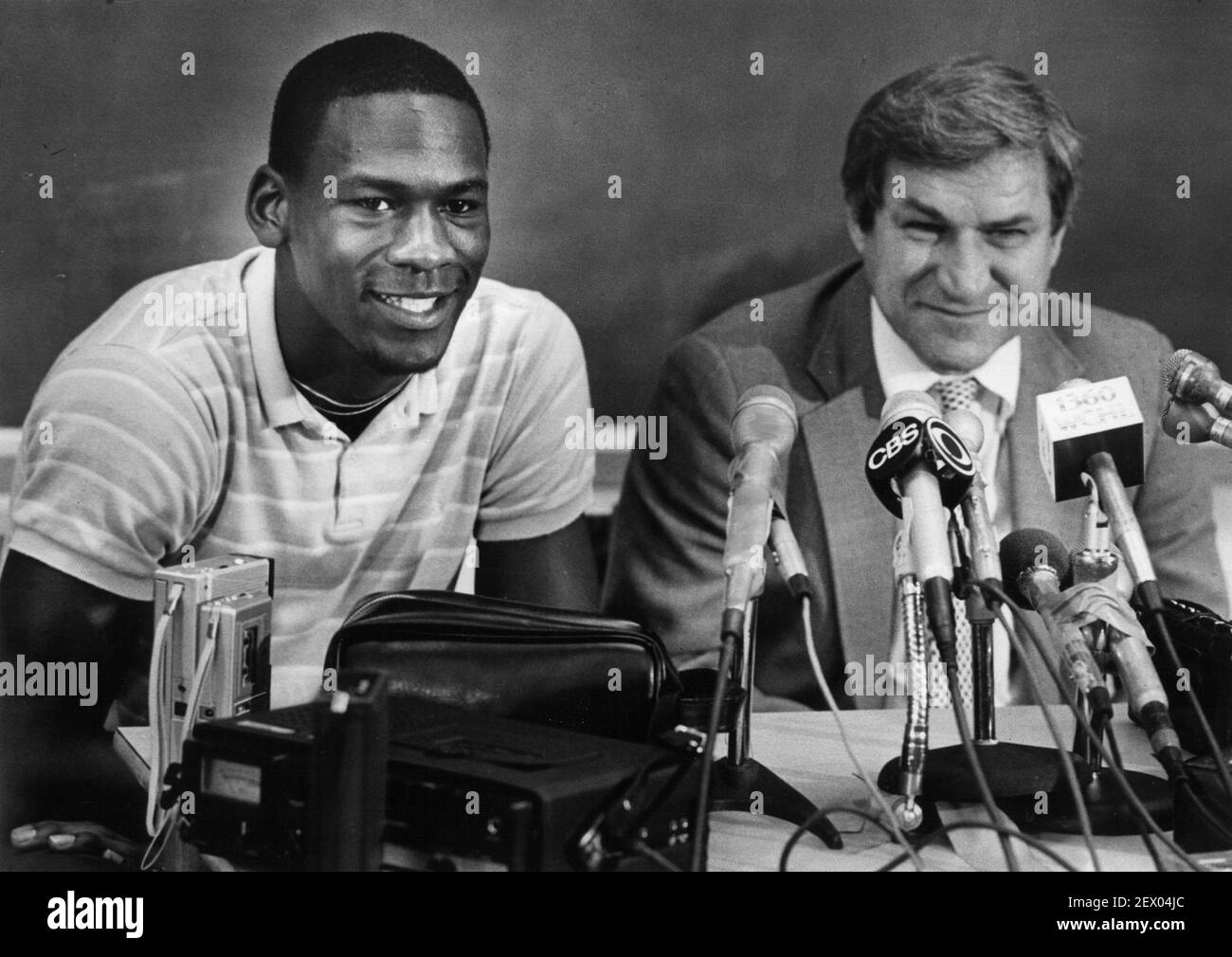 Michael Jordan es todo sonríe junto con el entrenador Dean Smith mientras Jordan anuncia en una conferencia de prensa de 1984 que él renunciará a su último año en la universidad para jugar baloncesto profesional. (Foto de Raleigh News & Observer/TNS) *** por favor use crédito del campo de crédito *** Foto de stock