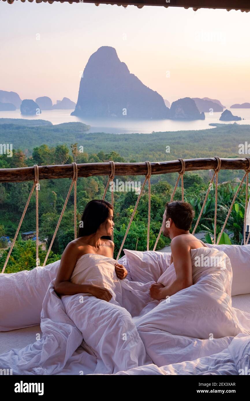 Phangnga Bay, pareja despertando en la cama en la selva de la naturaleza  mirando hacia el océano y la selva durante el amanecer en la cabaña de  madera en las montañas de