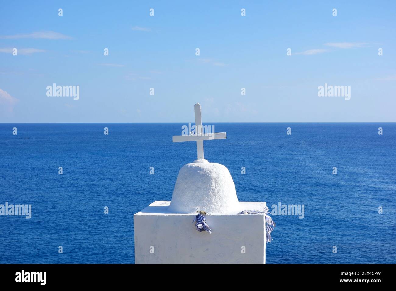 Una cruz religiosa con banderas griegas en ella, frente al mar egeo en la isla de Folegandros Foto de stock