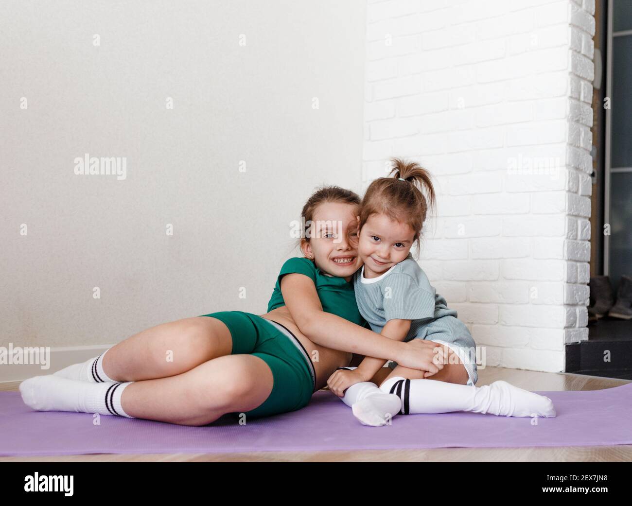dos niñas con ropa deportiva están sentadas en el suelo de y abrazándose Fotografía stock - Alamy