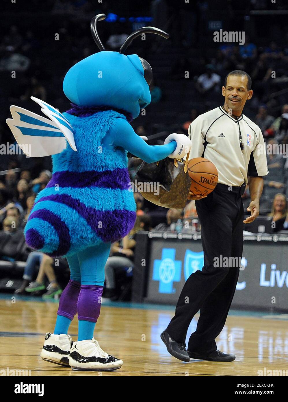 La mascota Hugo de Charlotte Hornets interactúa con el oficial Eric Lewis  durante un tiempo fuera como el anfitrión de Charlotte Hornets jugar a los  New York Knicks en acción previa el