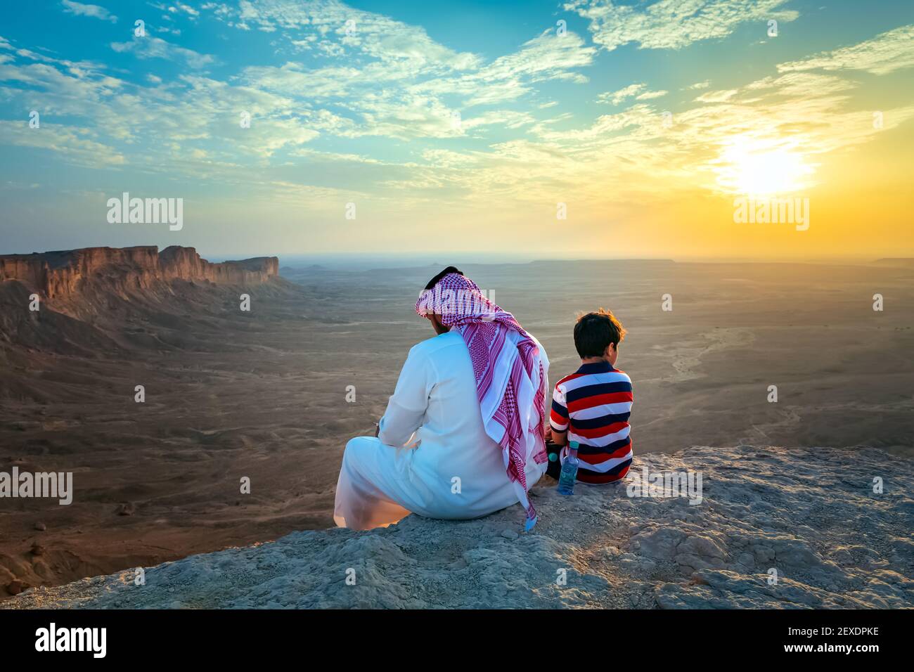 Un hombre árabe y su hijo sentados en Edge of the World, un punto de referencia natural y popular destino turístico cerca de Riyadh -Arabia Saudita.08-Nov-2019. Seleccione Foto de stock