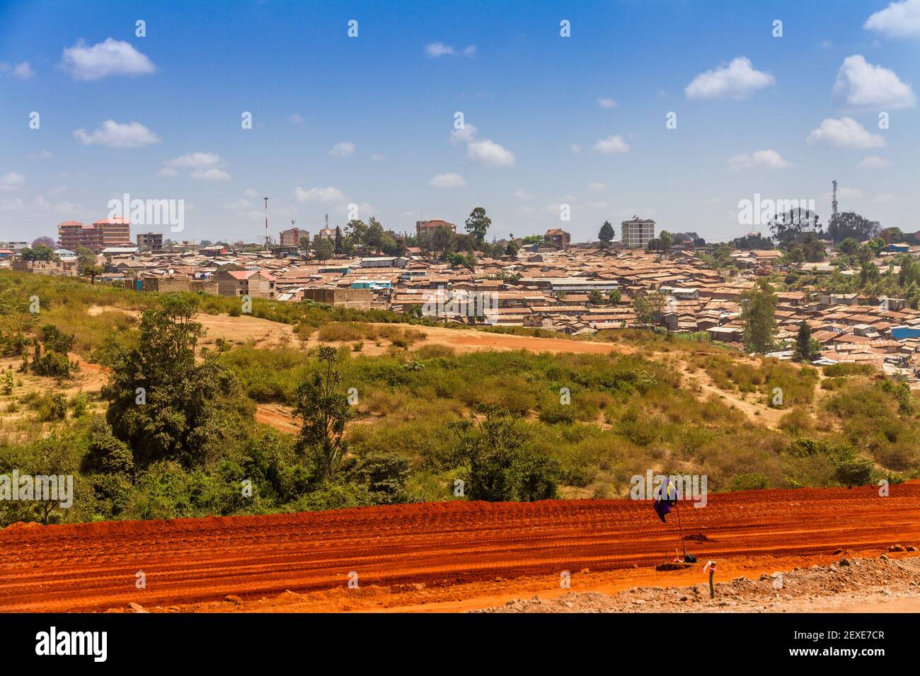 Un camino de tierra roja hacia los barrios de tugurios de Kibera en Nairobi, Kenia. Foto de stock