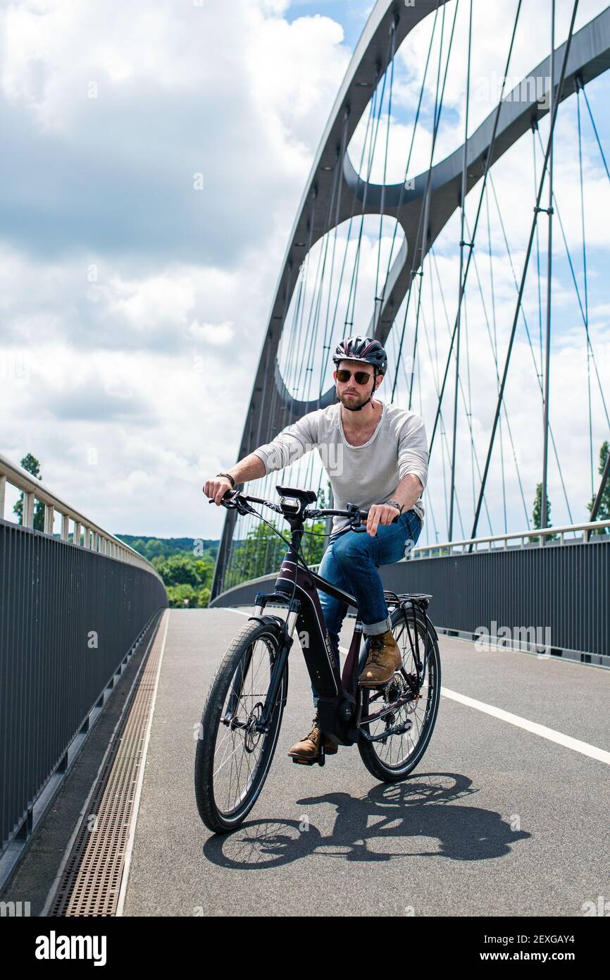Ciclista en bicicleta eléctrica está cruzando el puente del puerto este en Frankfurt am Main, Hessen, Alemania. Foto de stock