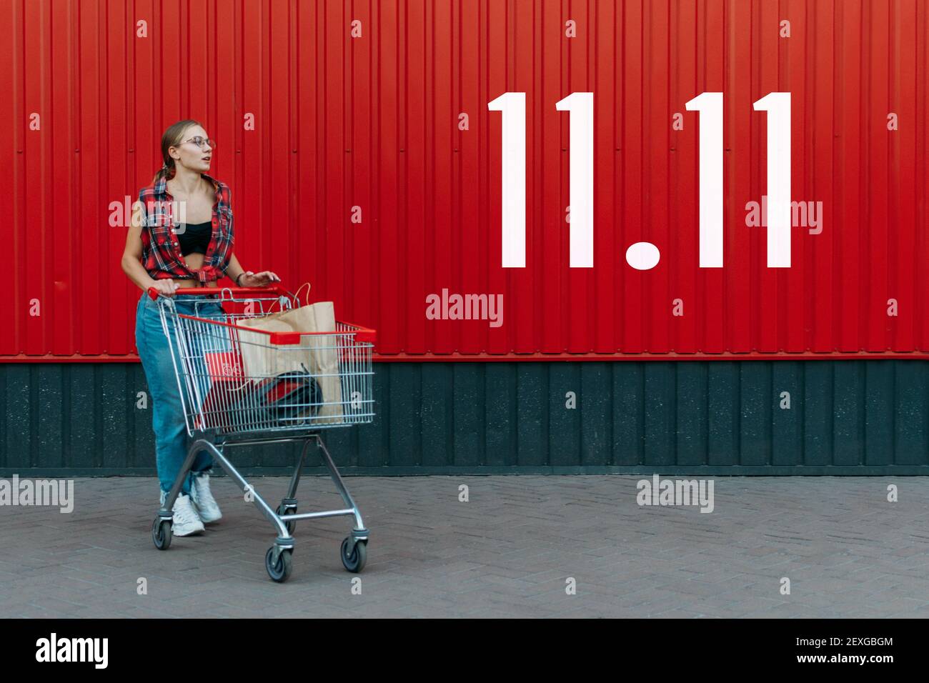 Chica Feliz Con Carrito De Compras En El Fondo De La Tienda De La Pared Roja Con Número De 1111 7536