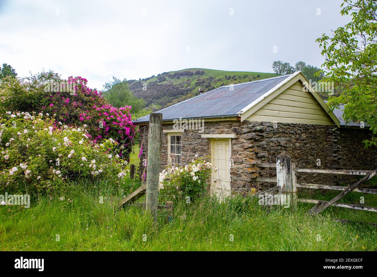 Una encantadora casa de campo de piedra histórica de los primeros colonos se encuentra junto a una carretera rural en Central Otago, Nueva Zelanda Foto de stock