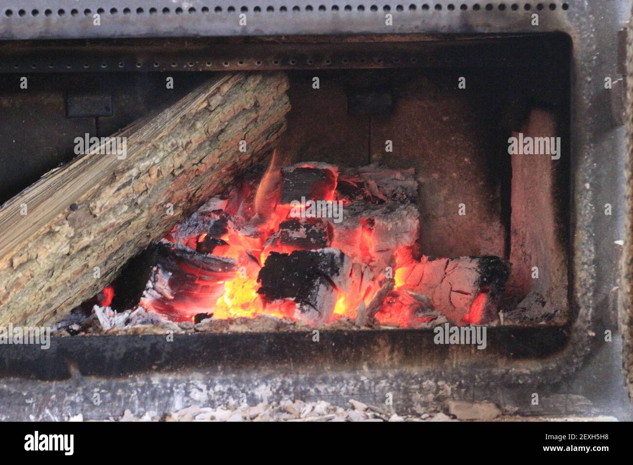 Agregar madera a una estufa de madera durante los fríos meses de invierno. Foto de stock