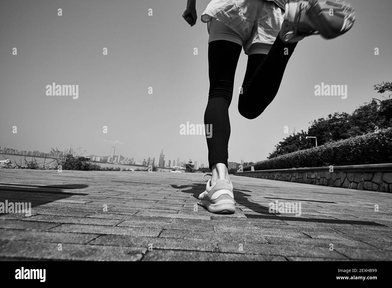 joven mujer adulta asiática corriendo jogging al aire libre, vista trasera y ángulo bajo, blanco y negro Foto de stock