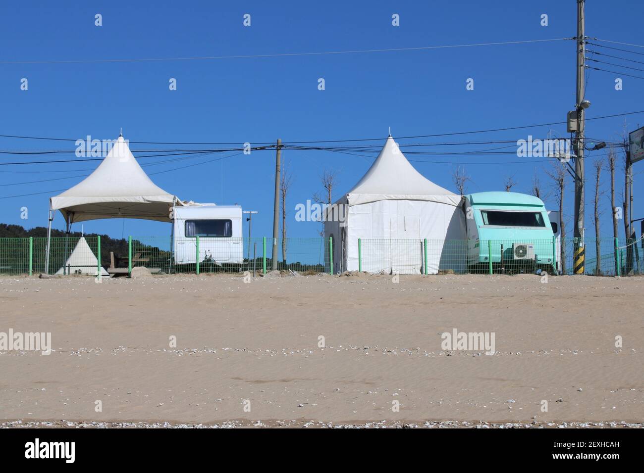 Vehículos de campamento azules y blancos y tiendas de campaña en la playa Foto de stock