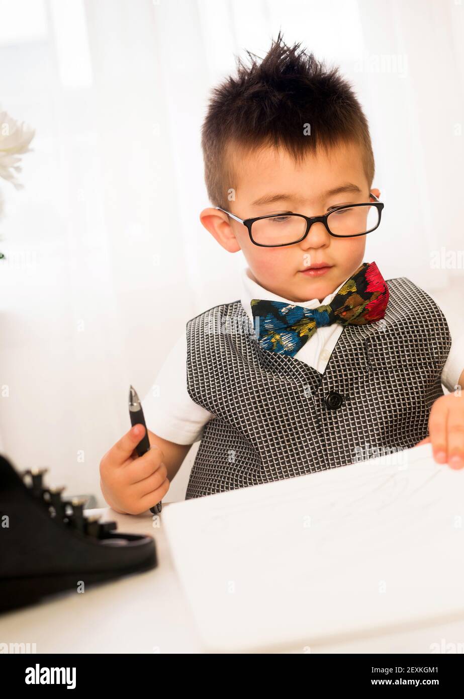 Young Boy juega papeles de firma de hombre de negocios intelectual en el escritorio Foto de stock