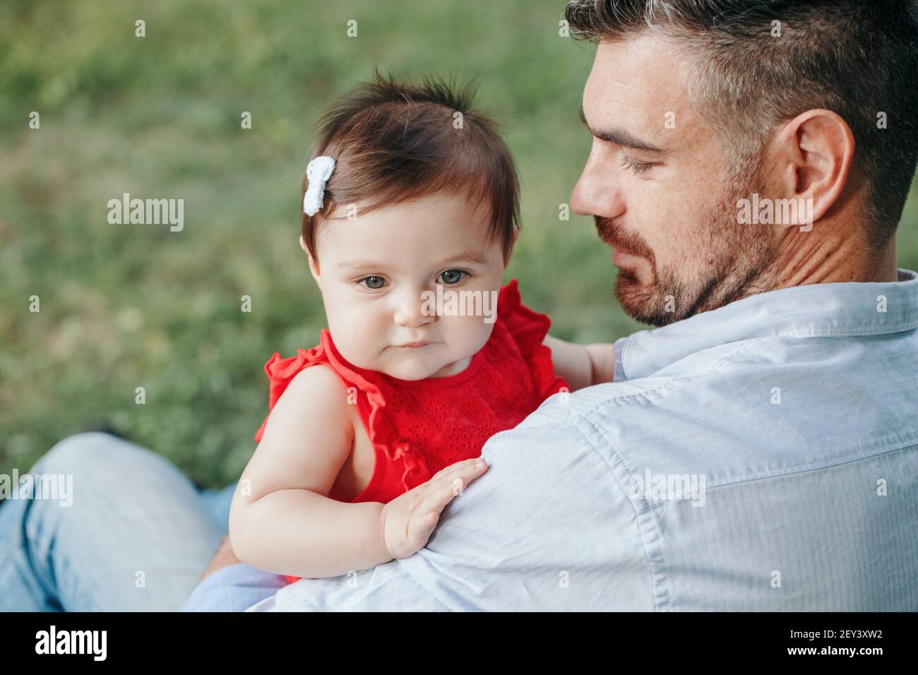 Edad media Caucásico orgulloso padre sosteniendo a bebé hija. Padre de  familia y su hija sentados juntos al aire libre en el parque el día de  verano. La vida con los niños