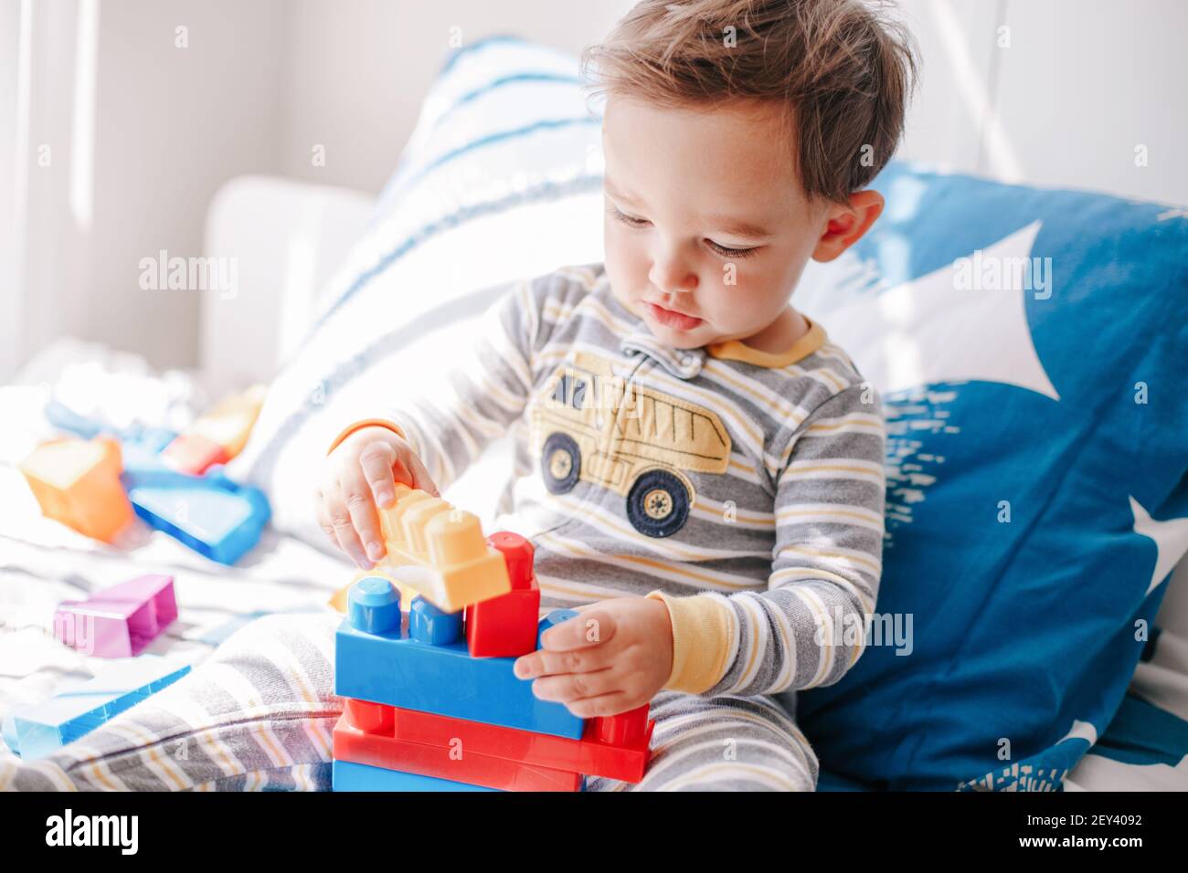 Lindo bebé niño jugando al edificio con bloques de apilar de juguetes de aprendizaje en casa. Educación en la primera edad. Los niños tienen el cerebro de la mano y el desarrollo de habilidades motoras finas. Foto de stock
