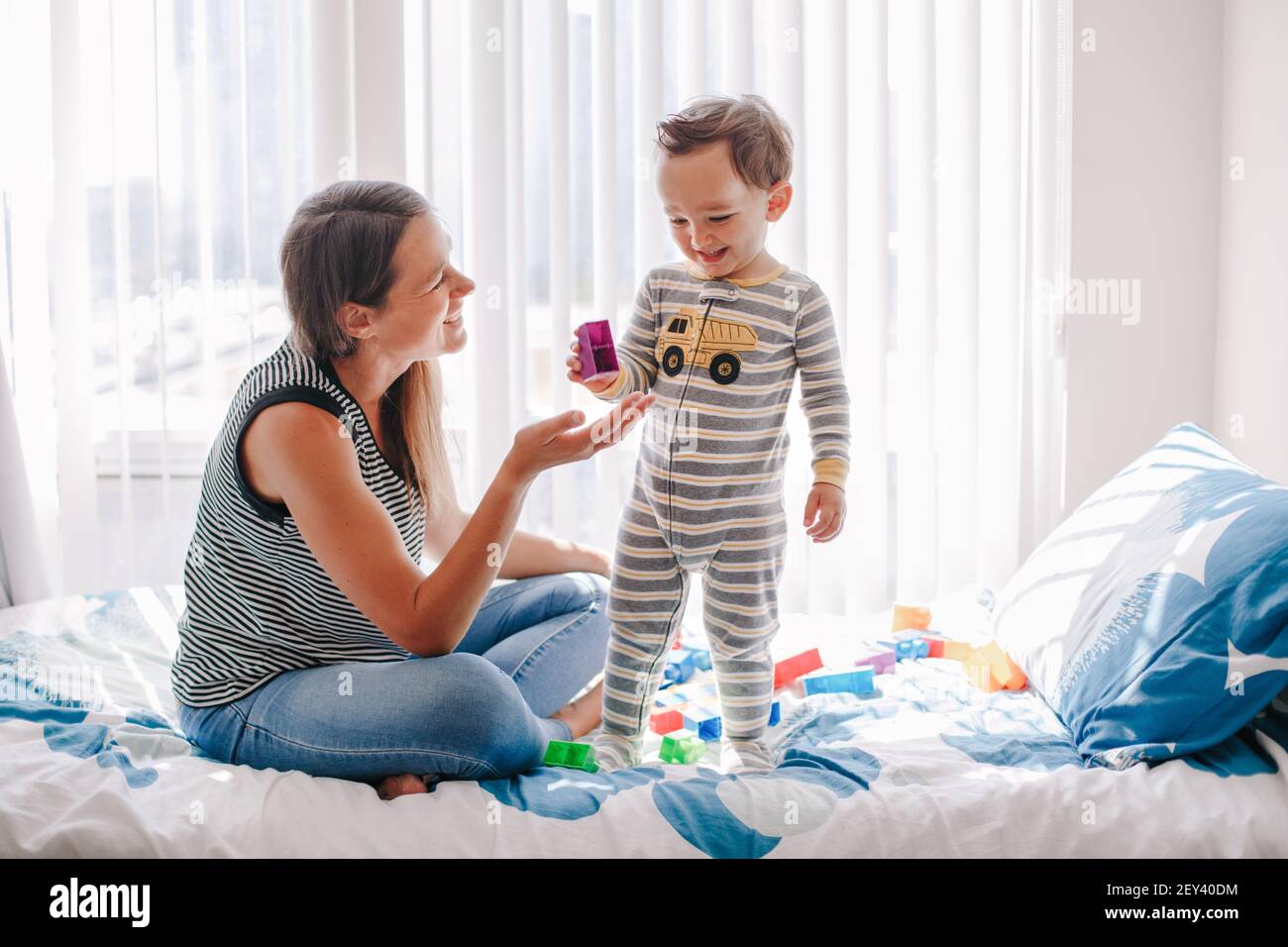 La madre y el bebé juegan al edificio con bloques de apilar de juguetes de aprendizaje en casa. Educación en la primera edad. Los niños desarrollan el cerebro de la mano y las habilidades motoras finas Foto de stock