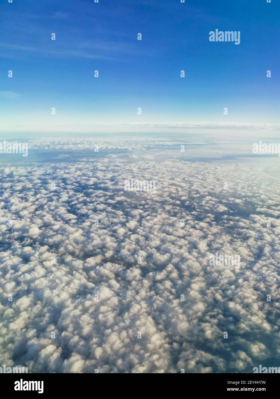 Una hermosa vista desde un avión sobre nubes blancas y esponjosas sobre el fondo de un cielo azul brillante, rascacielos de la ciudad abajo, vista superior, ver Foto de stock