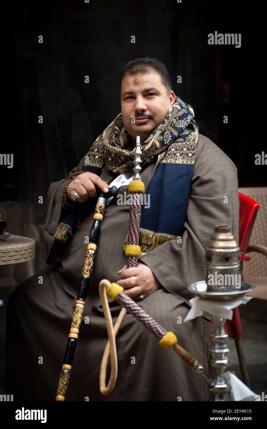 Retrato de un hombre egipcio local con vestido tradicional fumando una pipa de shisha en un café (ahwa) en el centro de el Cairo, Egipto Foto de stock