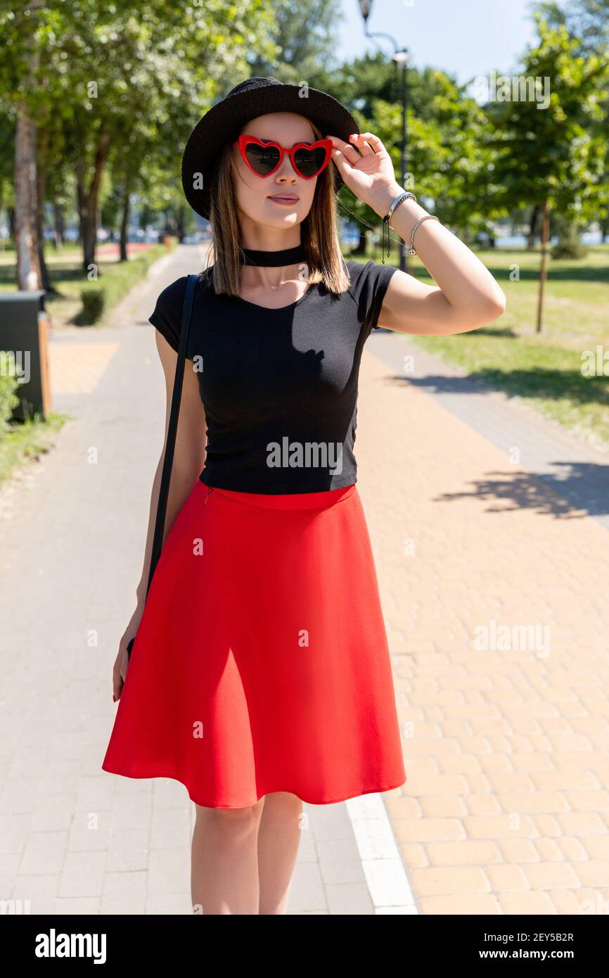 Retrato de mujer hermosa en camiseta negra y falda roja caminar en el  parque Fotografía de stock - Alamy