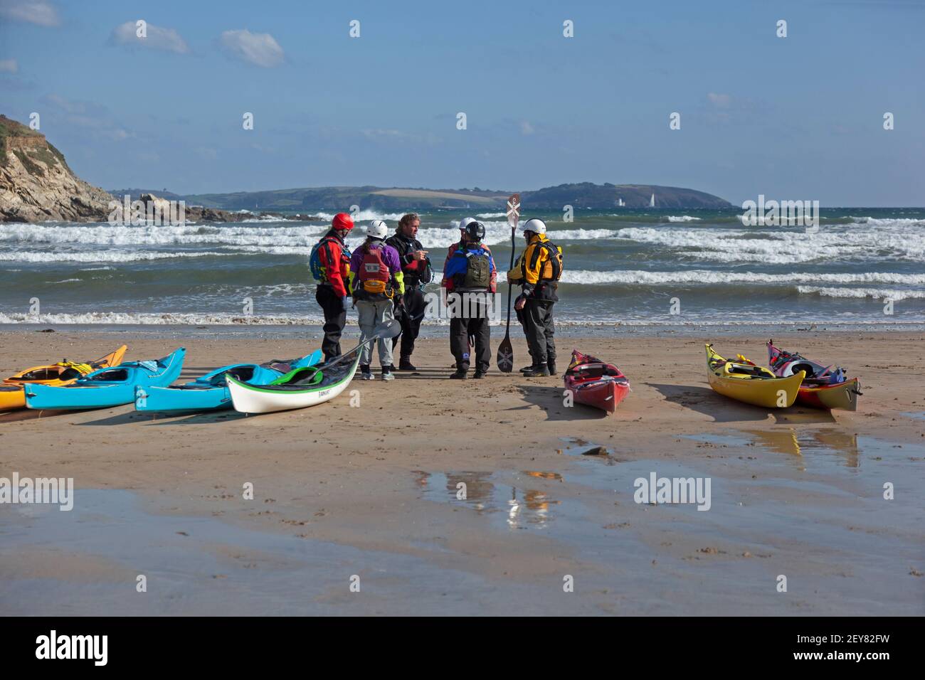 Clases de kayak de mar a un grupo de adultos en el playa en Maenport en Cornwall, Reino Unido Foto de stock