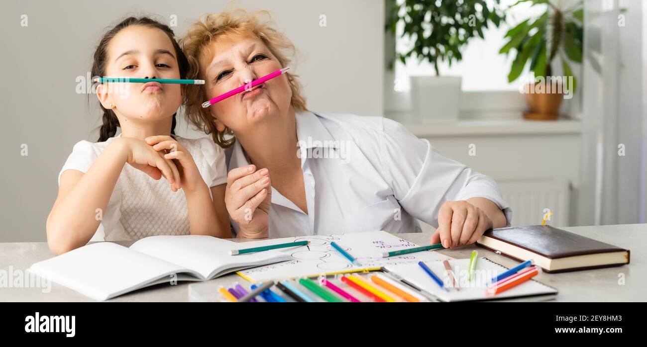 Mujer tutor o padre adoptivo mamá ayudar a la escuela caucásica lindo niño que hace la tarea sentado en la mesa. Diversas niñeras y niños aprendiendo a escribir Foto de stock