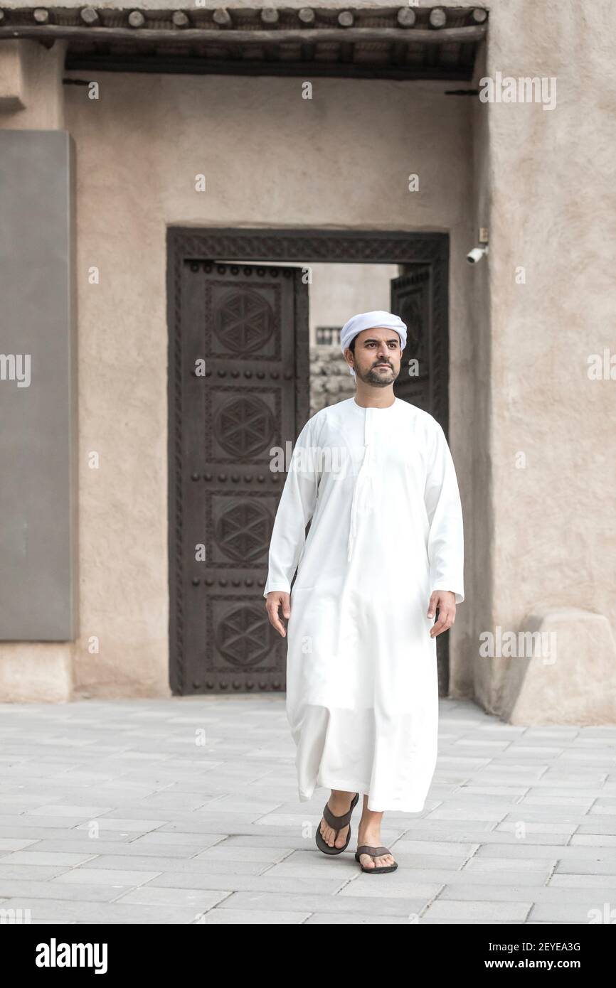 hombre árabe con ropa tradicional saliendo de una puerta En el histórico  distrito de Shindagha de Dubai Fotografía de stock - Alamy
