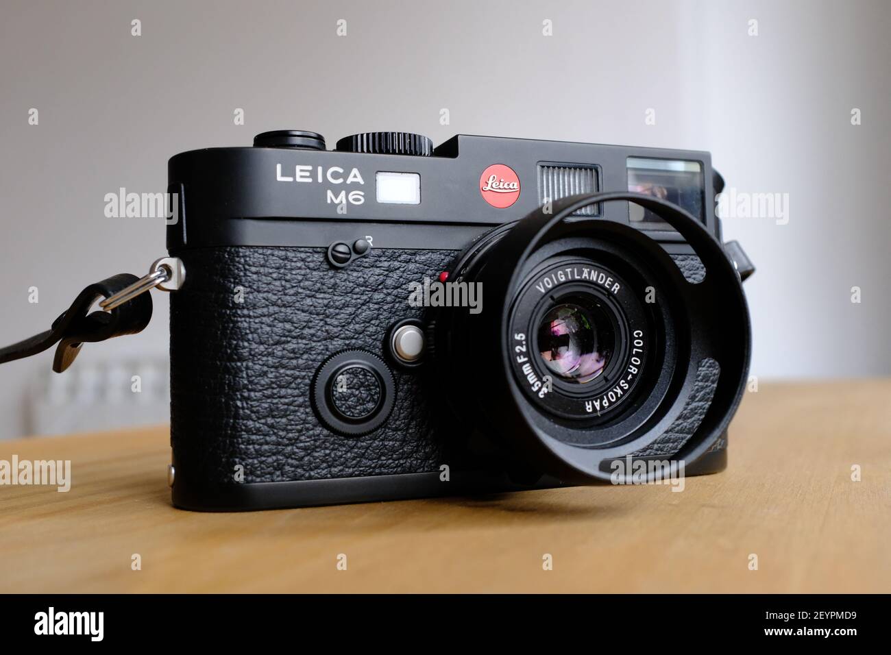 LONDRES - 6th DE MARZO de 2021: Una cámara de película analógica Leica M6 TTL modelo negro con una lente Voigtlander 35mm sobre una superficie de trabajo de madera. Foto de stock