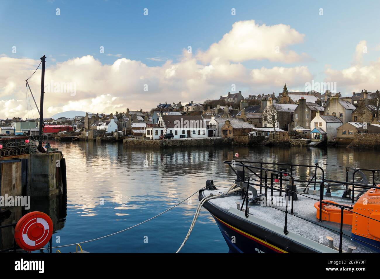 Mañana de invierno en el pequeño puerto de la ciudad escocesa con casas de época vistas al mar y paseo en bote salvavidas en primer plano Foto de stock