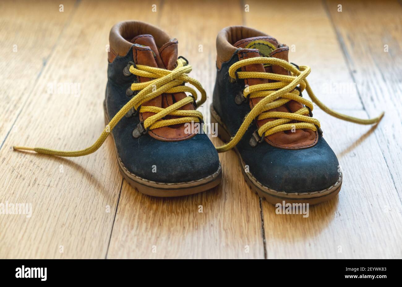 Niños botines de pequeño tamaño vista de primer plano. Zapatos de bebé cuero  de color azul con cordones de zapato amarillo sin atar en el suelo de  madera Fotografía de stock -