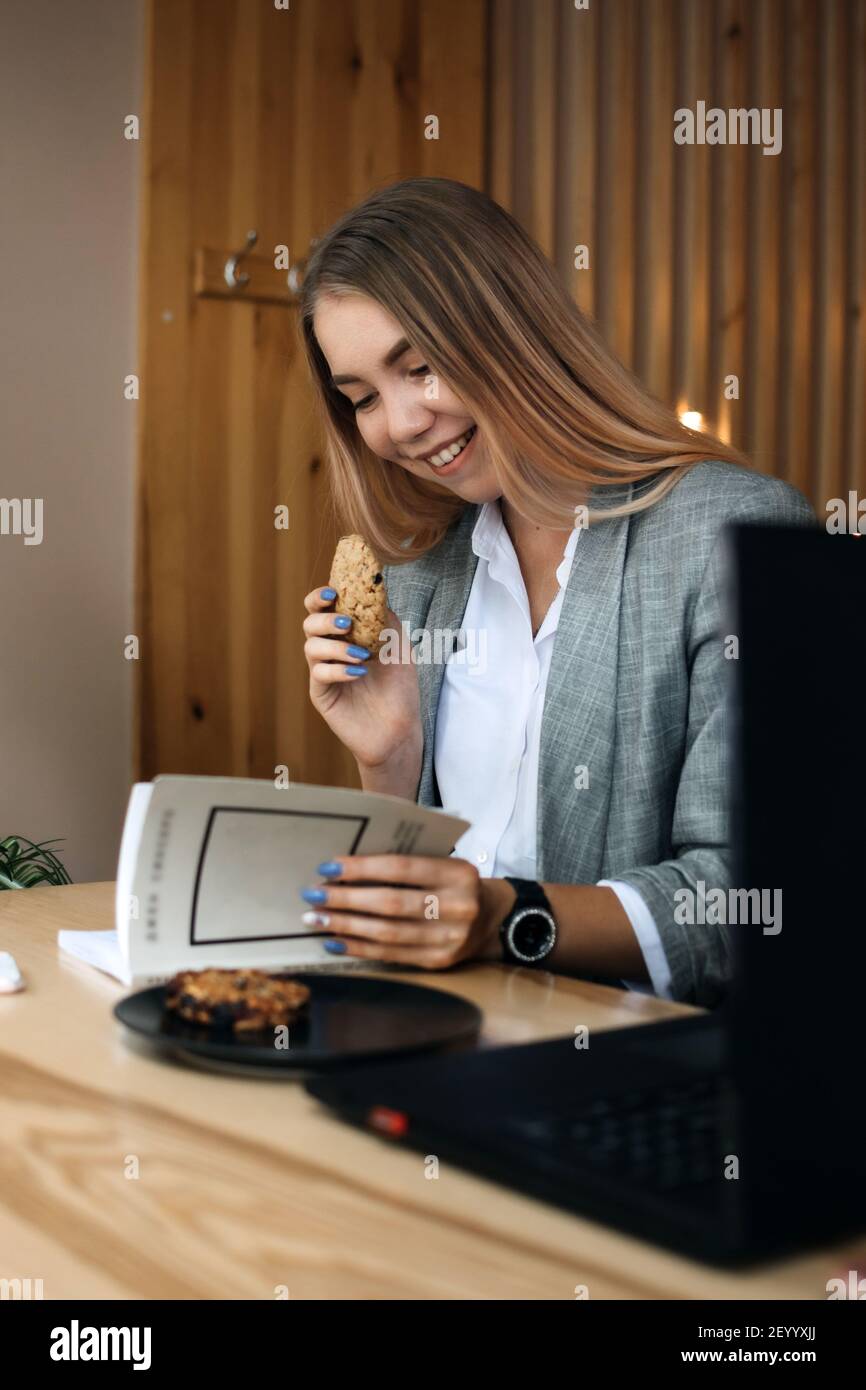 Alimentos para estimular el cerebro y la memoria. Alimentos vinculados a un mejor poder cerebral. Niña, adolescente, estudiante con libro abierto en sus manos y galletas de grano sano Foto de stock