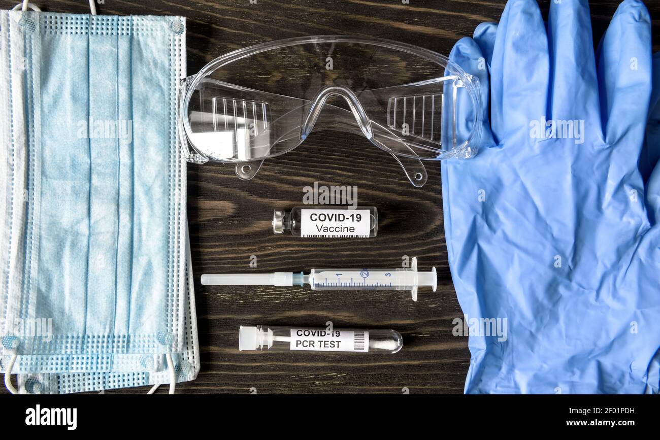 Kit médico de coronavirus COVID-19, vista superior del equipo personal (PPE), vacuna, jeringa y prueba de PCR. Composición plana de la máscara protectora, guantes Foto de stock