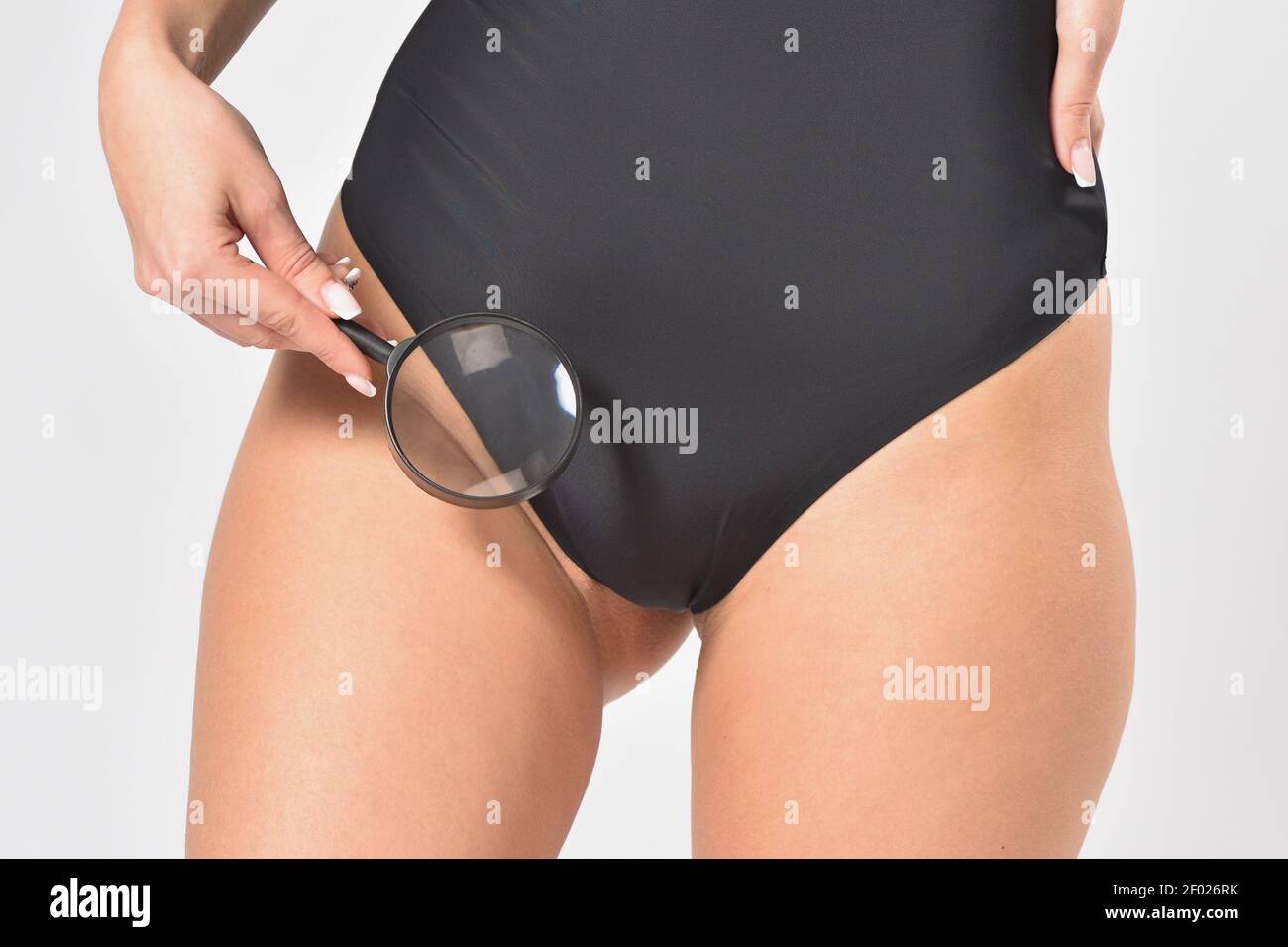 Mujer revisa su zona íntima del bikini con una lupa después de la depilación Foto de stock