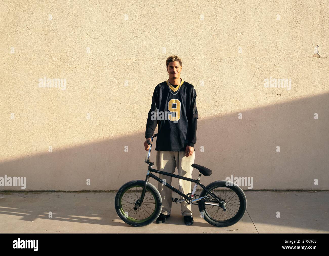Joven atleta de hipster étnico masculino en ropa fría sentado BMX bicicleta  mientras mira la cámara en la ciudad en el sol día Fotografía de stock -  Alamy