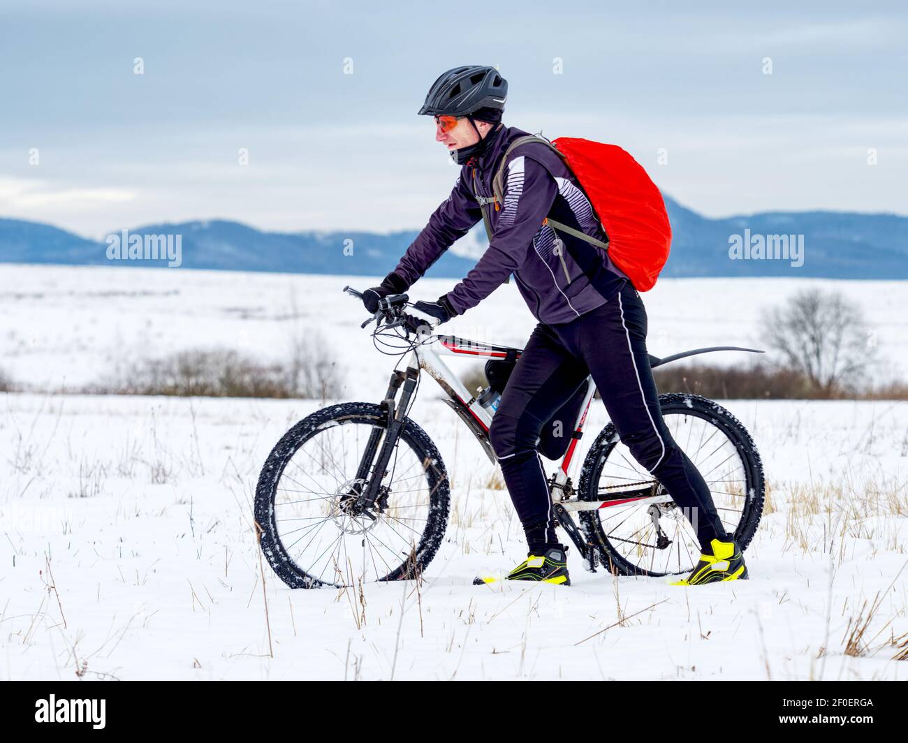 Ciclista en traje de deporte negro empujando la bicicleta de montaña en el  Snowy Trail. Concepto de Deporte extremo de Invierno y Ciclismo Enduro  Fotografía de stock - Alamy